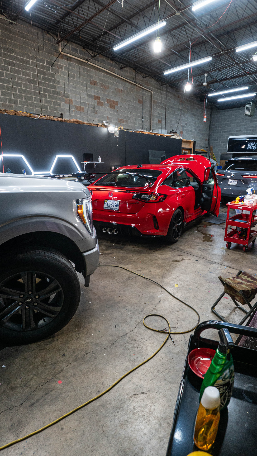 Red Honda with doors open inside the Skyline Customs workshop during a tint install