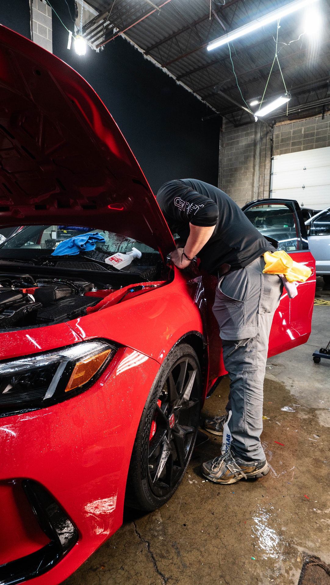 Skyline Customs technician performing finish work on a red vehicle inside the shop
